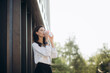 © Roman - Young female in white blouse standing on pavement near entrance at shop with coffee to go and looking at camera