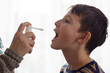 The child receives medication through a mouth spray for a sore throat