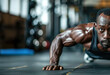 A dark-skinned athlete with an athletic physique does push-ups from the gym floor