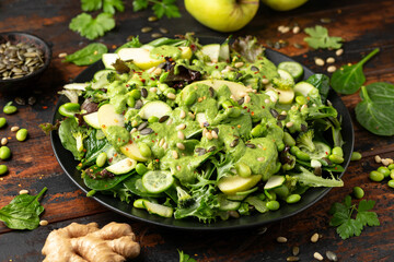 Wall Mural - Super green salad with spinach, broccoli, apples, cucumber and edamame beans served with avocado, apple cider vinegar and olive oil dressing, pine nuts and pumpkin seeds