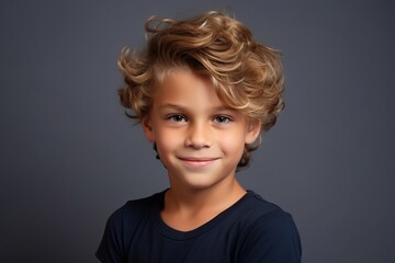 Portrait of a cute little boy with blond curly hair, over grey background.