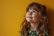 © Маргарита Вайс - happy adorable little girl with curly hair looking away on yellow background, closeup smiling face