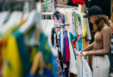 Fototapeta  - Teenage girl choosing a clothes at the evening bazaar.