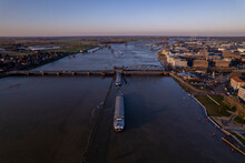 Aerial During Extreme High Water Level Of River IJssel In Zutphen, The Netherlands With Cargo Ships Waiting For The Steel Draw Bridge To Let Them Pass. Aerial Weather And Climate Concept.
