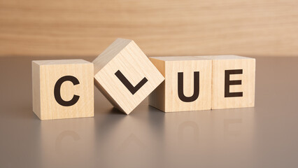 Poster - four wooden cubes with the letters CLUE on the bright surface of a brown table, business concept