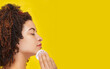 Profile of a woman with her eyes closed cleaning her face with cotton on a yellow background