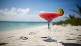 Fototapeta  - Freshly prepared delicious pink cocktail with a round piece of lime in a Margarita glass on the blurred seashore background