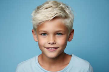 smiling little boy with blond hair and blue eyes over blue background