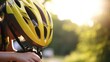 Closeup of a teens hand adjusting the ventilation openings on their yellow bike helmet.