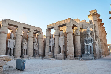 Seated statue of Ramesses II by the First pylon of the Luxor Temple, Egypt. Columns and statues of the Luxor temple main entrance, first pylon, Egypt