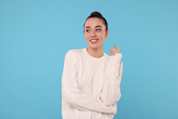 Poster - Beautiful young woman in stylish warm sweater on light blue background