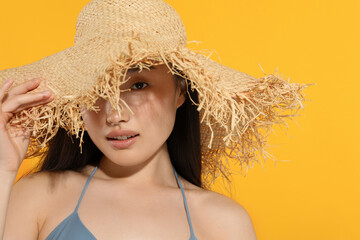 Canvas Print - Beautiful young woman in straw hat on orange background, space for text