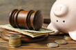 Piggy bank with judge gavel and money on brown wooden background. Concept of bankruptcy