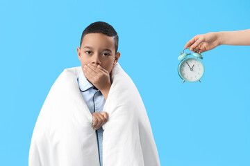 Poster - Sleepy little African-American boy and female hand with alarm clock on blue background