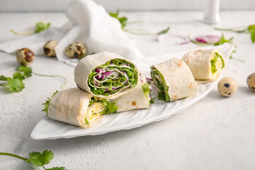 Plate of tasty lavash rolls with onion and egg on light background