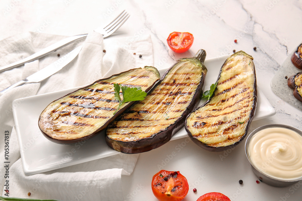 Plate with delicious grilled eggplants, sauce and tomatoes on light background