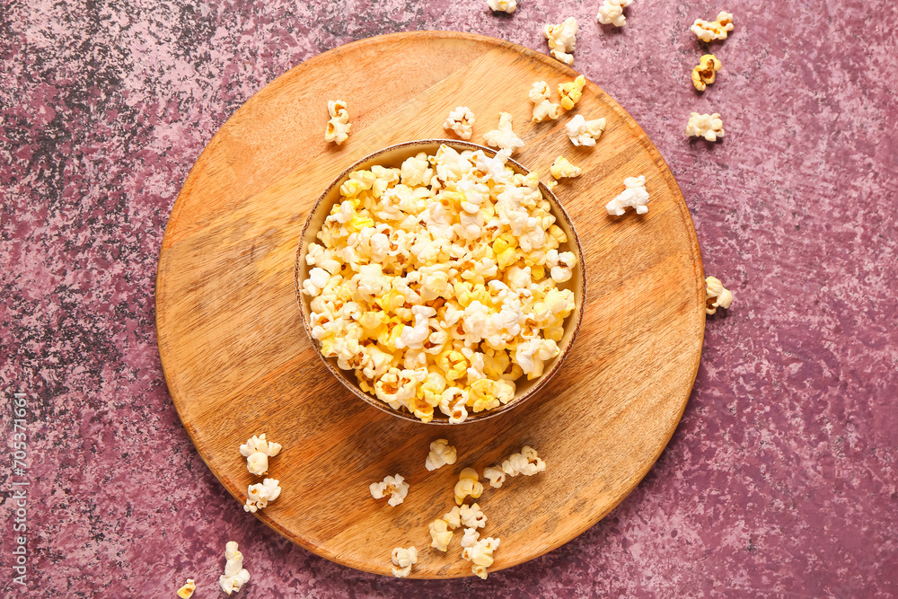 Bowl with tasty popcorn on purple background