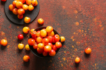 Bowl and board with sweet yellow cherries on dark table