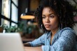 © FrameFrenzy - Young serious concerned African American businesswoman sitting at desk looking laptop computer in contemporary corporation office. Business technologies concept. Close up, Generative AI