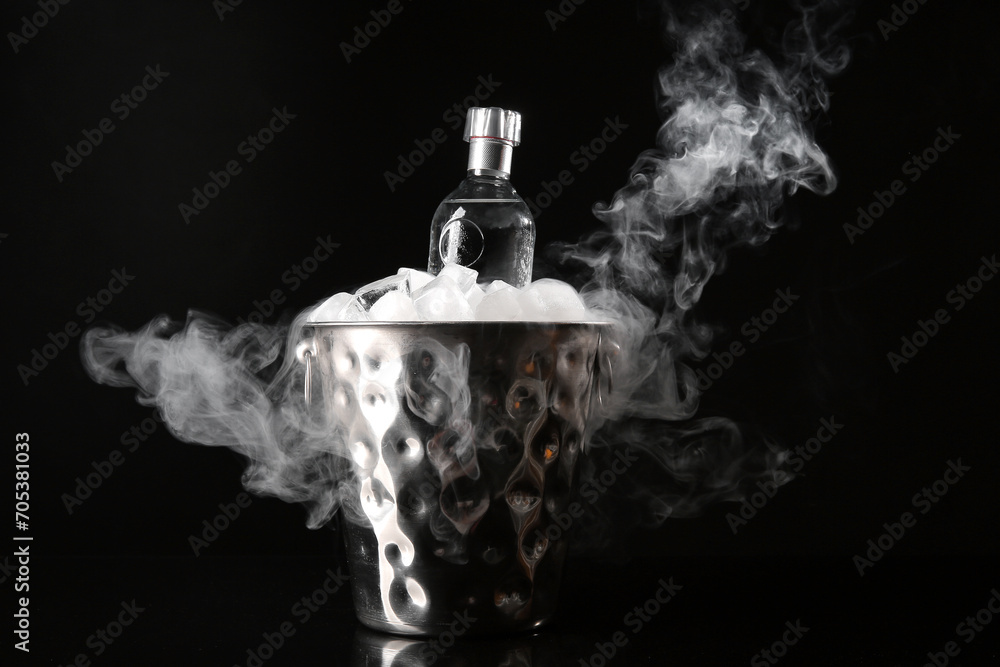 Bucket with ice and bottle of cold vodka on black background