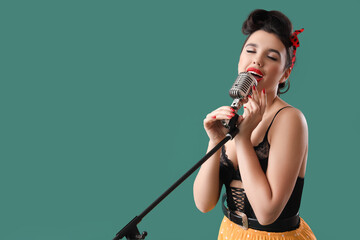 Wall Mural - Young pin-up woman with microphone singing on green background