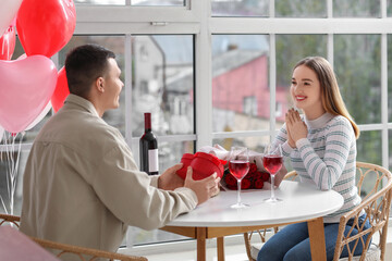 Sticker - Beautiful young couple with glasses of wine and gift box celebrating Valentine's Day at home