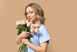 Fototapeta Tulipany - Pretty young woman with bouquet of beautiful roses on brown background
