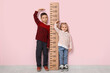 © Pixel-Shot - Cute little children measuring height near pink wall