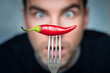 © diy13 - a man is afraid to eat hot peppers. ridiculous expression of a man with hot chillies in his hand