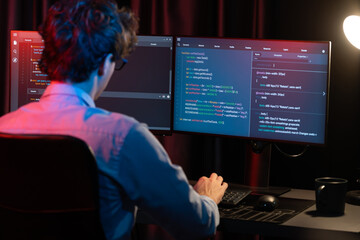 Working IT developer concentrating online software development information on surrounded by coding application pc screens, creating program for firmware on website at neon modern office home. Gusher.