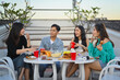 © Prathankarnpap - Group of young friends having fun talking and drinking at rooftop party in evening