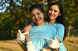 © Prathankarnpap - Two cheerful women pointing finger on volunteer title text on t-shirt while standing outdoor