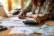 © milkyway - Female accountant working and calculating about finance document report on desk at home office