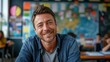 © ND STOCK - Portrait of smiling male teacher in a class at elementary school looking at camera with behind them is a backdrop of a classroom background