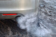 Car exhaust pipe smoking in cold weather. Engine warming up at idle in winter season. Smoke from car pipe exhaust, exhaust smoke.