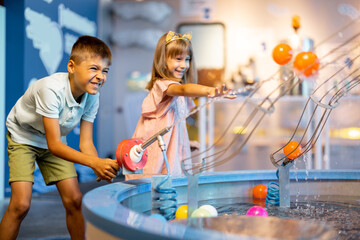 Wall Mural - Little boy and girl play with balls, learning physical phenomena in an interesting way, having fun in a science museum with interactive models