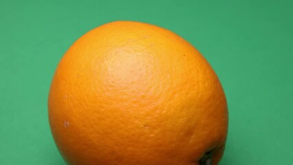 Canvas Print - Whole ripe orange fruit hand held shake rotate green background