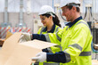 © chokniti - Professional worker team in safety uniform, supervisor inspector in packaging stock order at cardboard factory warehouse, piles of stacking paper manufacture, recycling industrial production
