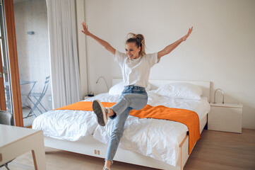 Wall Mural - Young girl in jeans and white tshirt having fun in bedroom