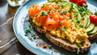 A gourmet breakfast toast served on a stylish blue plate. The toast is topped with smoked salmon and scrambled eggs. Fresh avocado slices and  cherry tomatoes are neatly arranged beside the toast.
