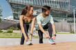 © muse studio - Sporty couple tying shoelaces, getting ready to run, with a futuristic building in the background.