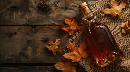 maple syrup bottle surrounded by autumn leaves on a wooden table