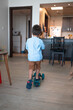 Tiny explorer: Cute toddler's blue push scooter adventures at home