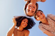 © Dasha Petrenko - Funny multiracial smiling teenager gilrs standing and looking down at camera. Group of happy cheerful female friends in casual clothes having fun together outdoors. Low angle view. Copy space.