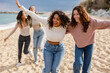 © PintoArt - group of multiethnic friends on vacation play running on the beach