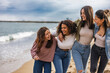 © PintoArt - group of multicultural friends standing in a row looking at their friend laughing on the beach