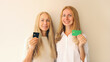 Portrait of happy smiling caucasian middle aged mother or sister and adult daughter holding plastic credit bank card together on studio background
