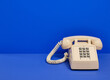 © Dima - Beige retro phone with gray buttons on a blue background. Copy space for text.