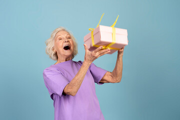 Canvas Print - Excited senior caucasian woman with open mouth throwing gift box