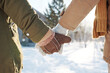 Close-up of hands in mittens and gloves and warm winterwear of affectionate couple standing in front of camera or taking walk